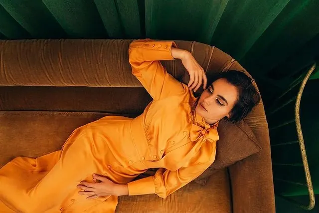 Woman in Orange Jumpsuit on Sofa