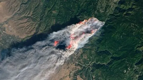 Aerial view of California wildfire with smoke plume, photographic, dark