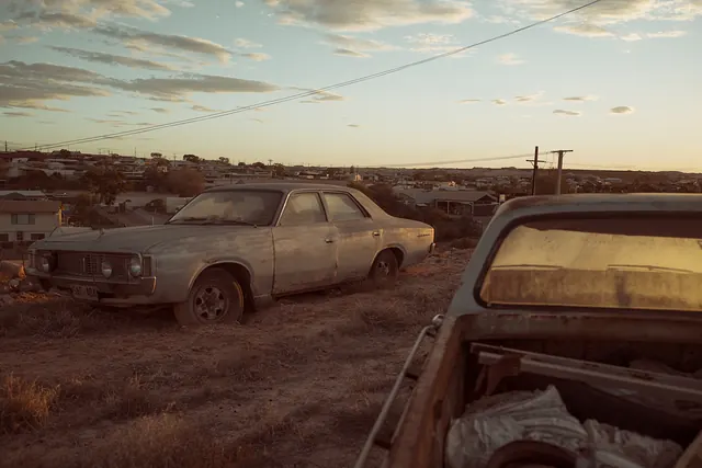 Abandoned cars in desert landscape, photographic, editorial, warm
