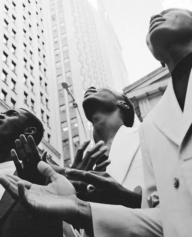 Black and white group portrait of suited men with expressive hands, photographic, editorial, monochrome