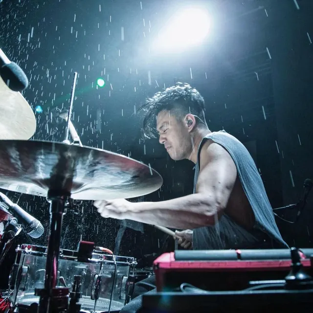 Intense drummer under dramatic stage lighting, photographic, dark