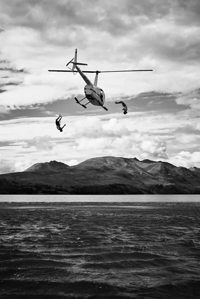 Skydivers leaping from helicopter over mountain lake, photographic, monochrome, monochrome