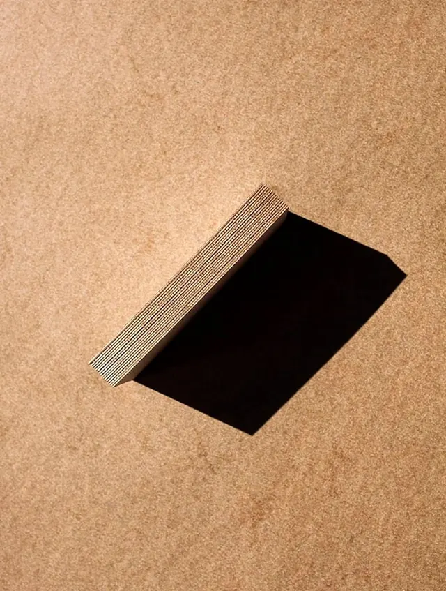 Layered paper stack with strong shadow, minimal, photographic, warm