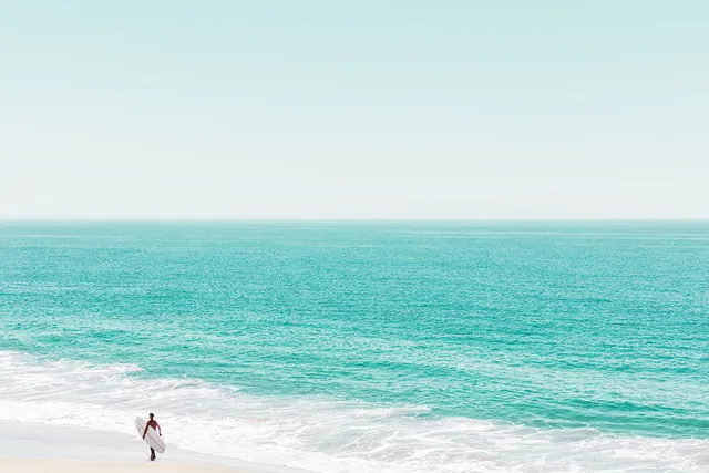 Minimal turquoise ocean beach with lone surfer, minimal, photographic, vibrant