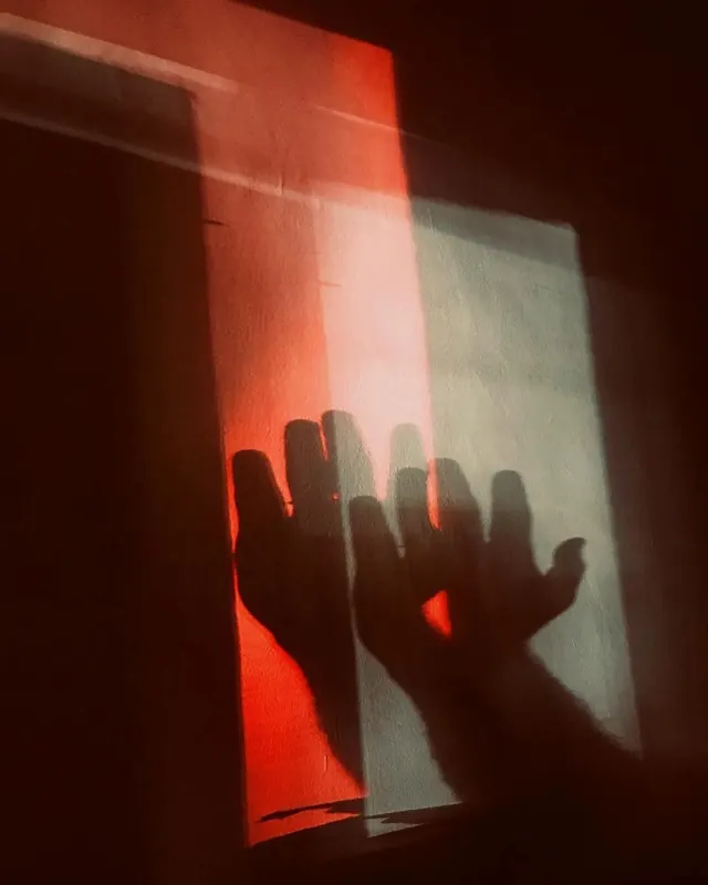 Dramatic hand shadow in red light, photographic, dark