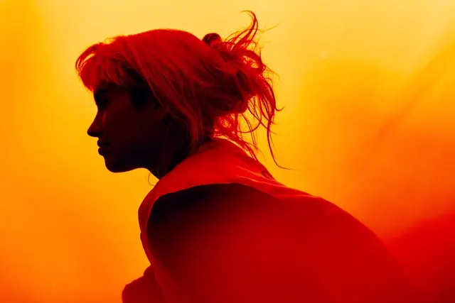 Silhouette portrait in orange gradient light, minimal, photographic, warm