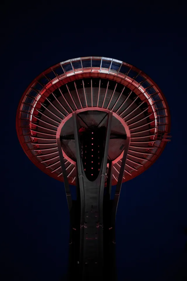 Space Needle observation deck lit red at night, photographic, geometric, dark
