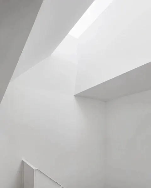 Bright white minimalist interior with angled skylight, minimal, swiss, light