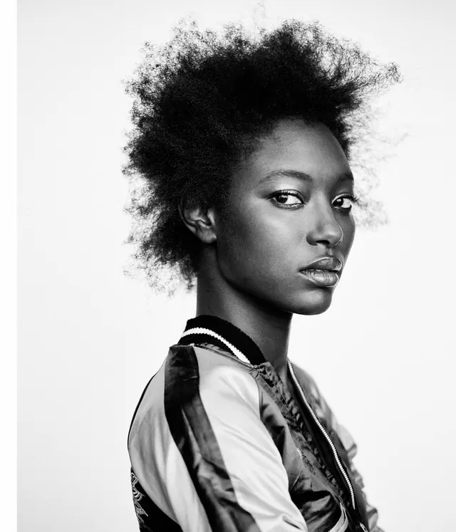Portrait of person with textured hair and layered clothing, photographic, minimal, monochrome