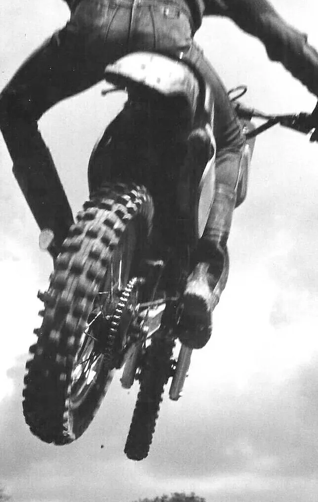 Dirt bike rider jumping against sky, photographic, dramatic, monochrome