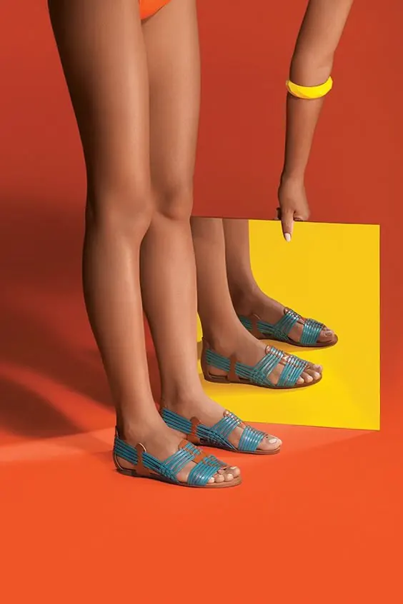 Blue strappy sandals on bright orange, minimal, editorial, vibrant
