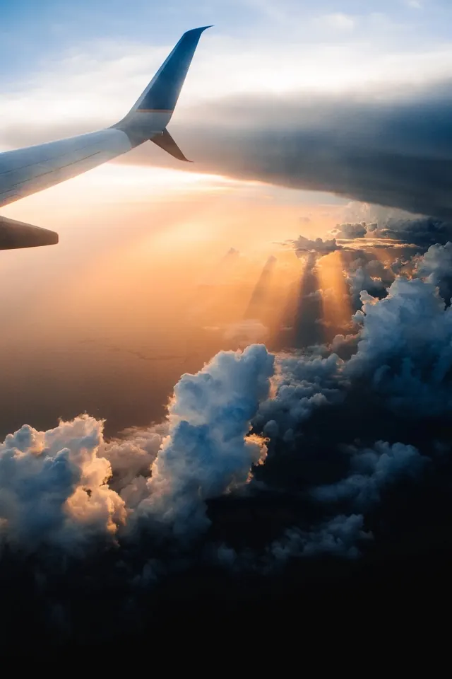 Airplane Wing Above Clouds at Sunset