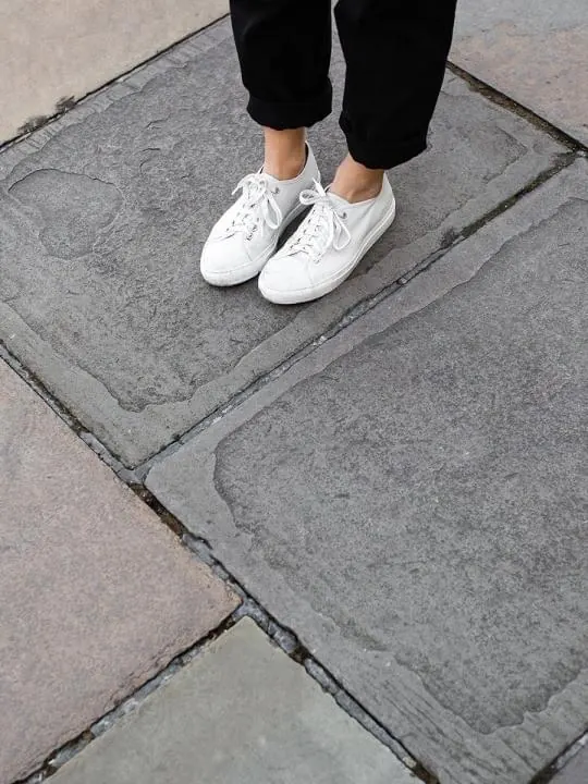 White sneakers on stone pavement, photographic, minimal, light