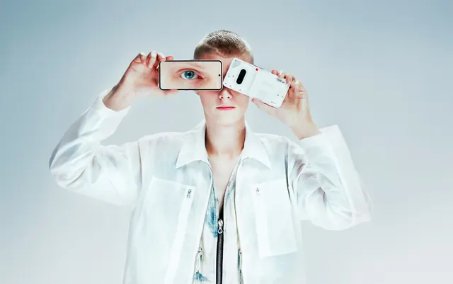 Person holding smartphone with face overlay