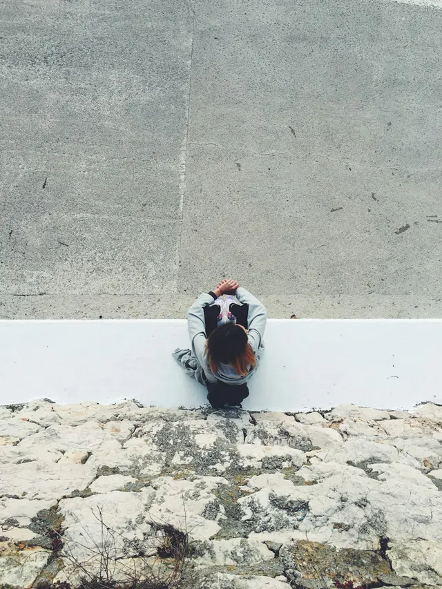 Person Sitting on Concrete Ledge