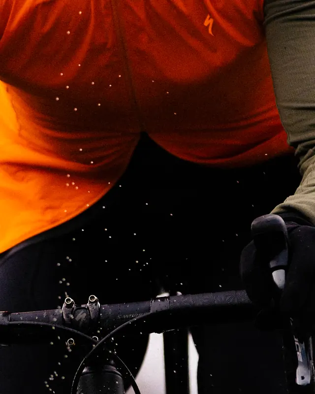 Cyclist orange gilet action close-up, photographic, technical, vibrant