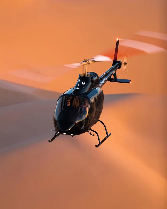 Black helicopter over desert dunes, photographic, cinematic, warm