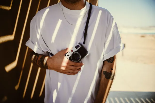 Person holding film camera by seaside, photographic, warm