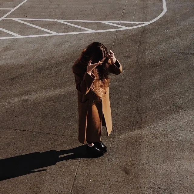 Overhead camel coat on asphalt, photographic, editorial, warm