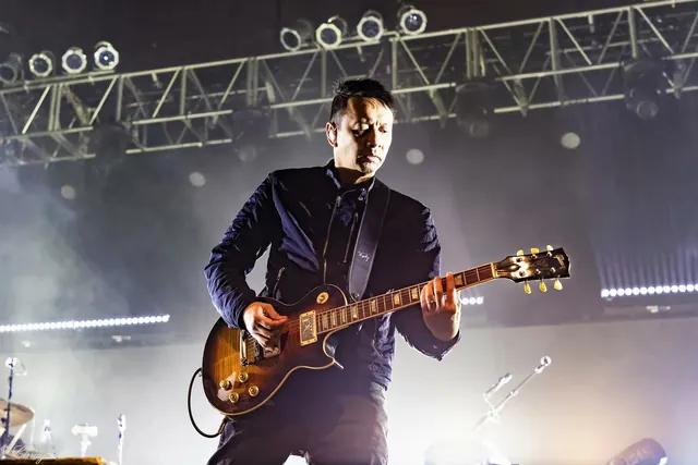 Concert guitarist with sunburst Les Paul, photographic, dark-mode, dark