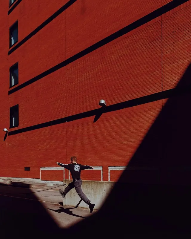 Man jumping past red brick wall, photographic, minimal, vibrant