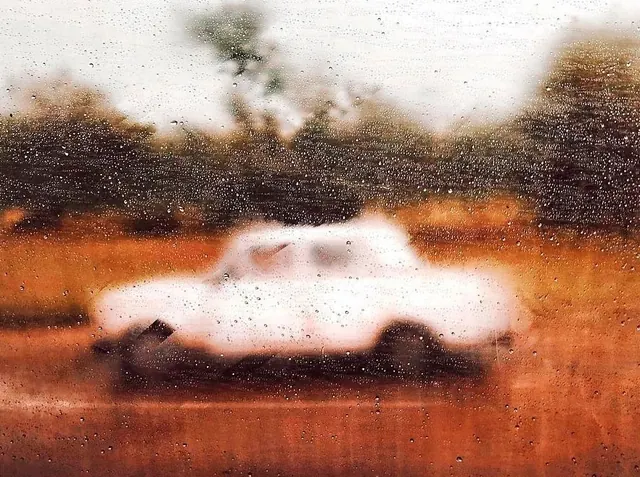 Vintage car through rain-streaked glass, photographic, organic, warm