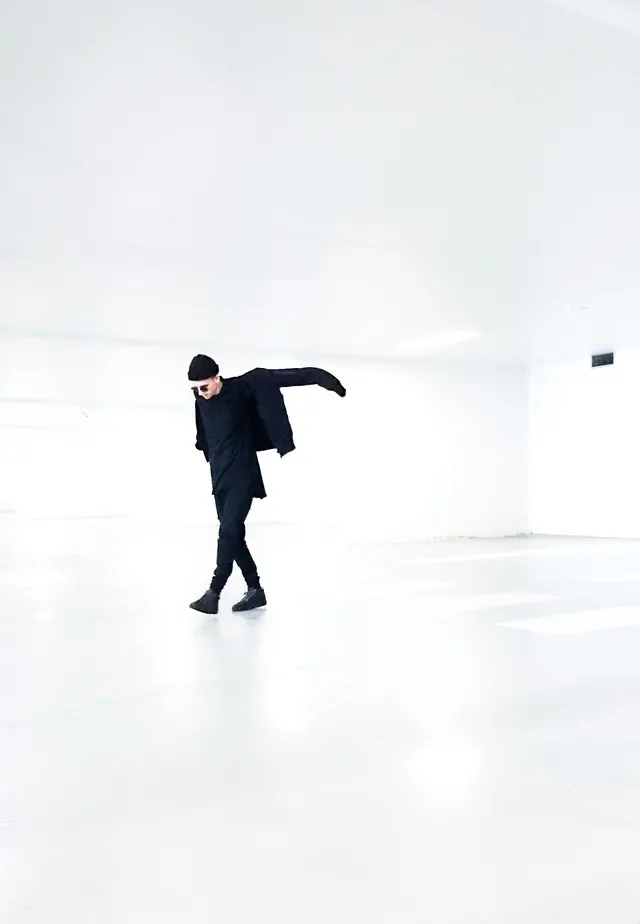All-black figure in white void, minimal, photographic, monochrome