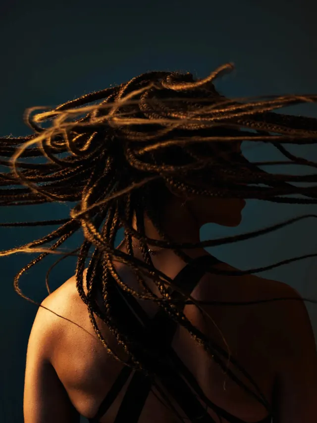 Braids in motion with warm rim light, photographic, dark-mode, dark