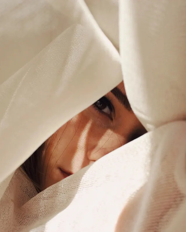 Fabric-framed eye portrait, photographic, minimal, warm