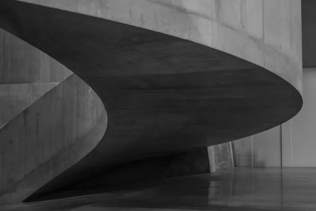 Curved concrete staircase study, minimal, brutalist, monochrome