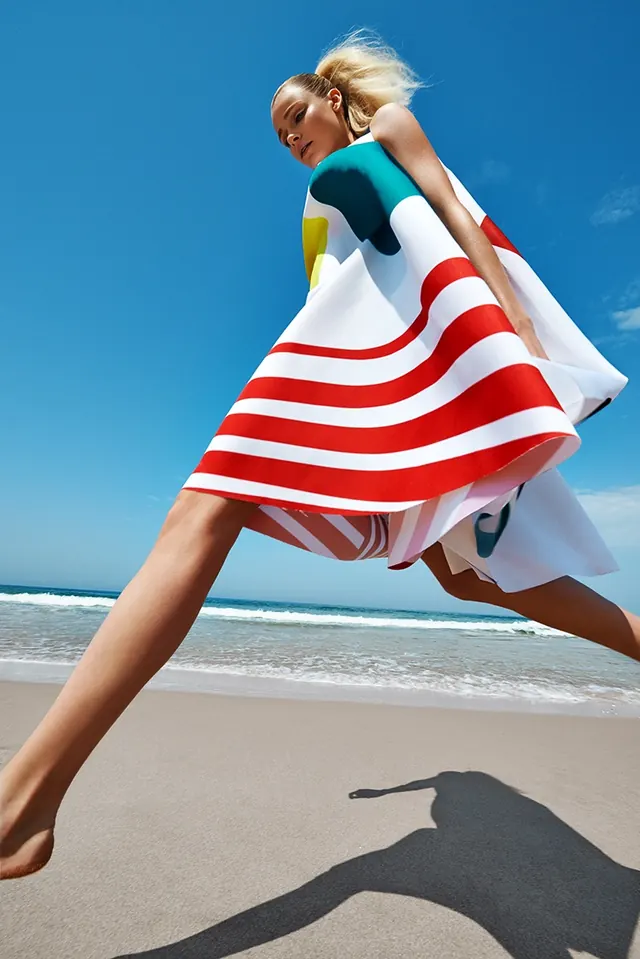 Beach fashion jump in graphic dress, photographic, playful, vibrant