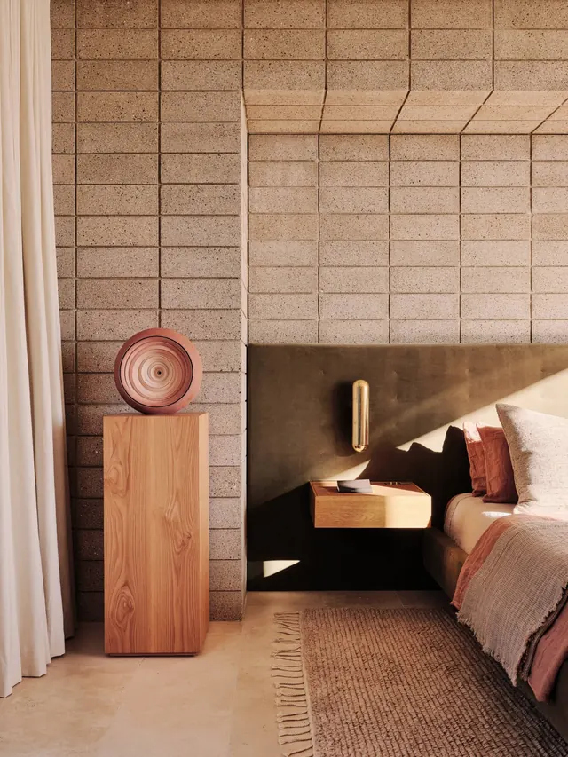 Concrete block bedroom with velvet headboard, minimal, organic, warm