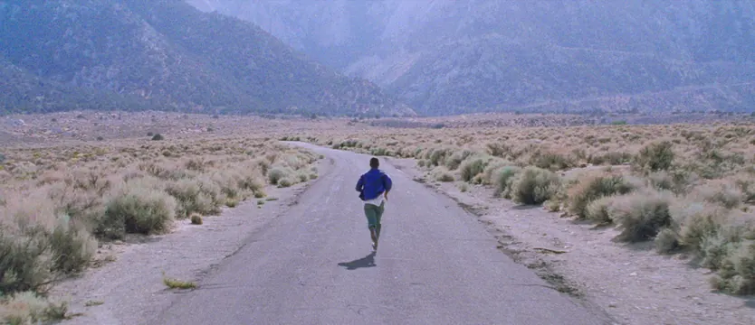 Lone runner on desert highway still, photographic, cinematic, muted