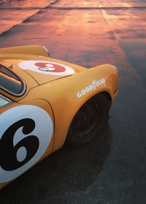 Yellow vintage race car in wet sunset reflection, retro, photographic, warm