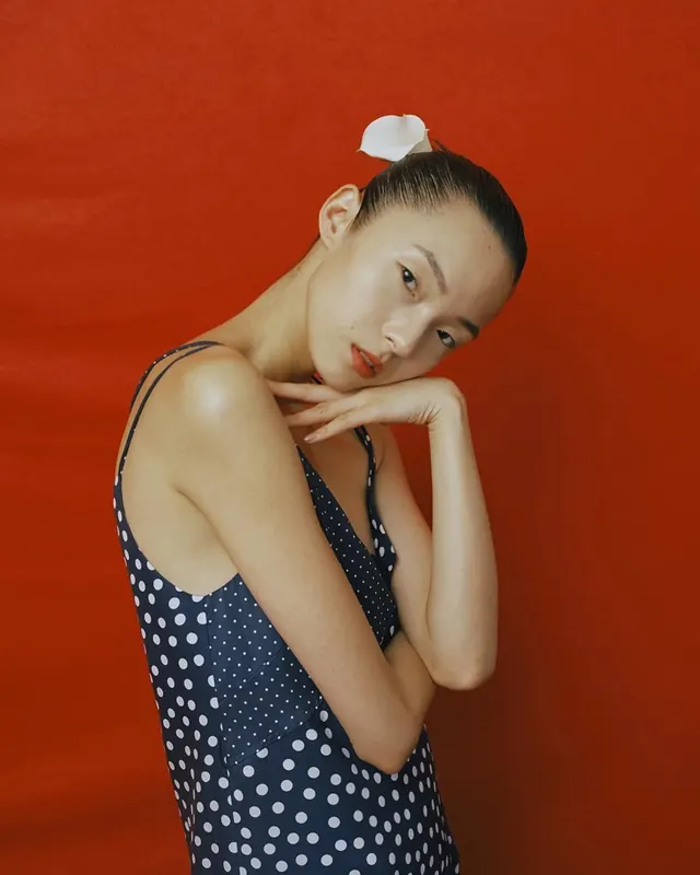 Polka-dot dress on red studio backdrop, editorial, minimal, vibrant