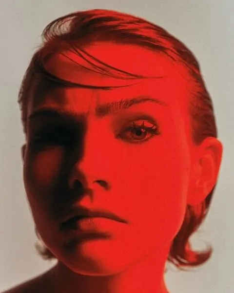 Red-gel chiaroscuro face close-up, editorial, photographic, vibrant