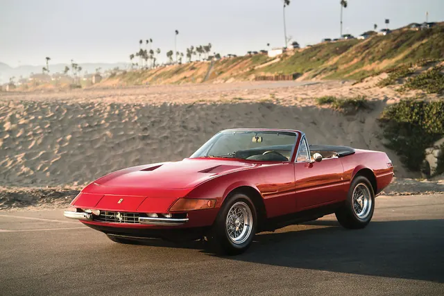 Red convertible sports car on beach, photographic, editorial, warm
