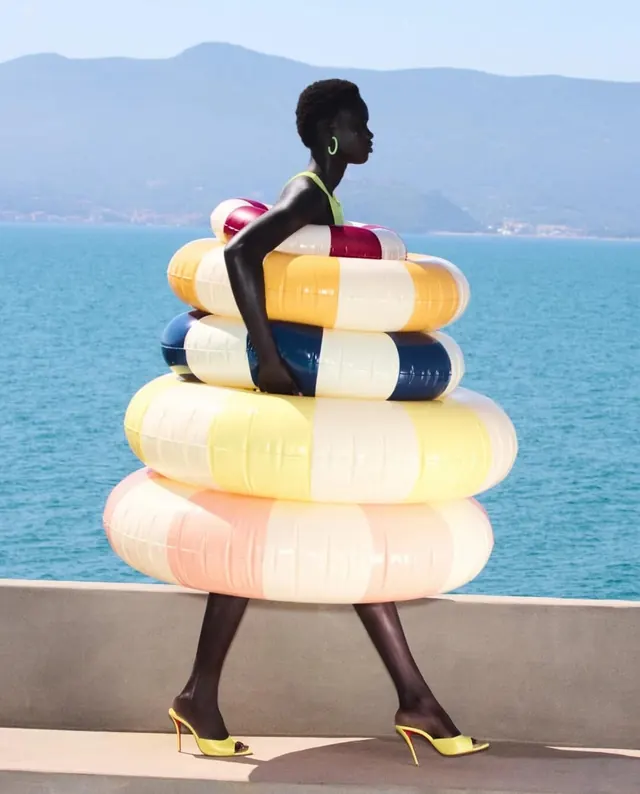 Woman with stacked colorful swim floats, photographic, playful, vibrant
