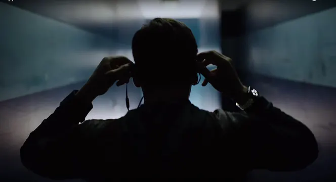 Silhouette of man adjusting headphones in blue-lit corridor, minimal, dark-mode, dark