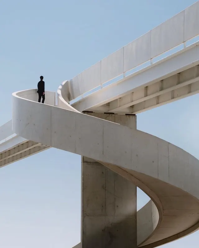 Spiral concrete ramp with lone figure, minimal, photographic, light