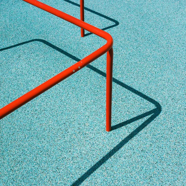 Red metal tubing on turquoise textured surface, photographic, geometric, vibrant