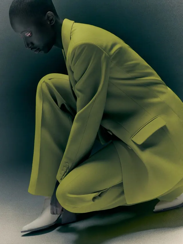 Model in lime green suit crouching, minimal, editorial, vibrant