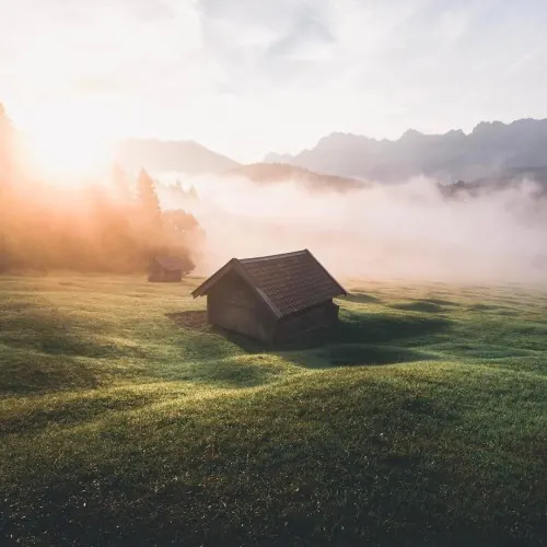 Mist-covered mountain cabin at sunrise