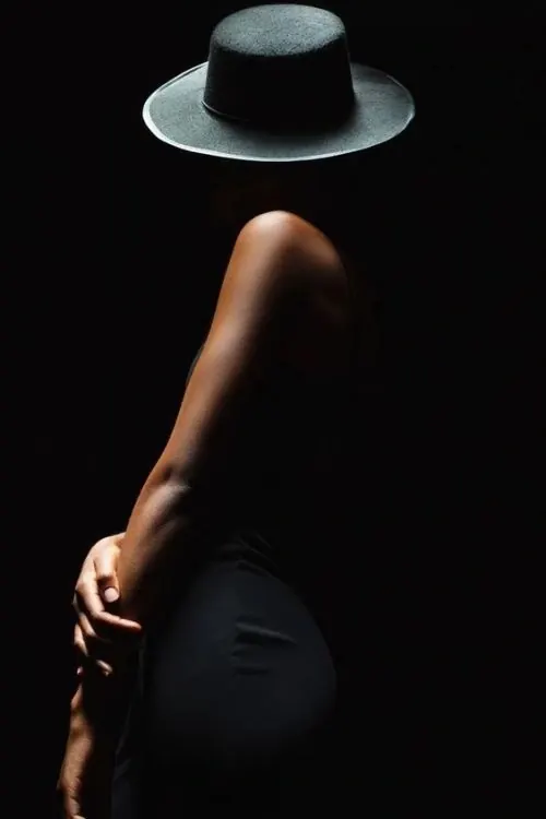 Silhouetted figure in wide-brim hat against black, minimal, dark-mode, dark