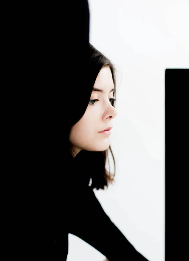 Profile portrait of woman in black turtleneck with strong shadows, minimal, editorial, light