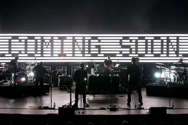 Concert stage with band and bright horizontal light bar, minimal, dark-mode, dark