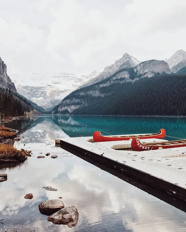 Red canoe on snowy mountain lake dock, photographic, cool