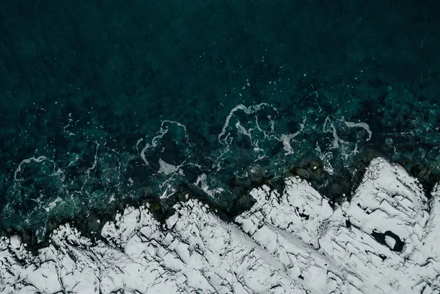Aerial snowy rocky shoreline, photographic, minimal, cool