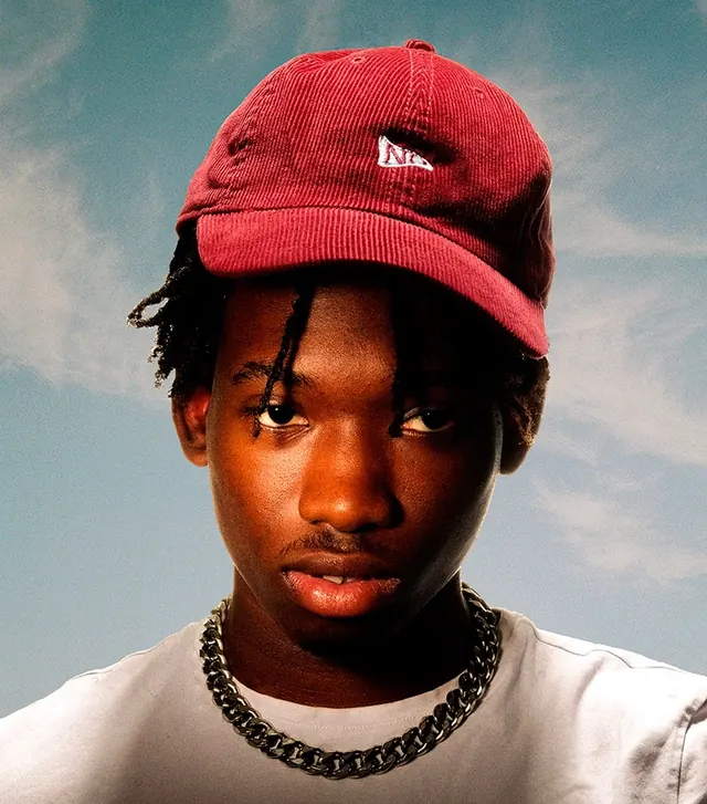 Red corduroy cap portrait against sky, photographic, editorial, vibrant