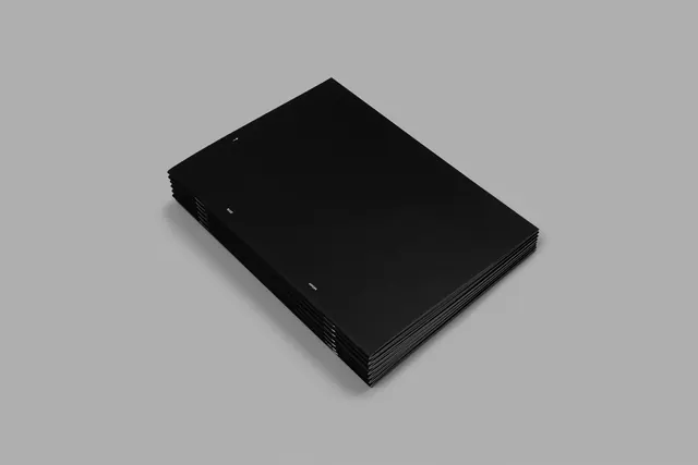 Stacked black stitched booklets on grey, minimal, editorial, monochrome